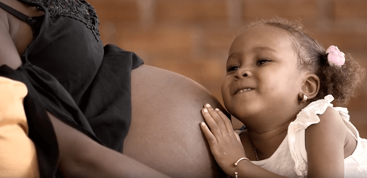 A girl hugs her mother's pregnant belly