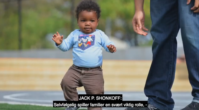 A toddler boy walks next to his father