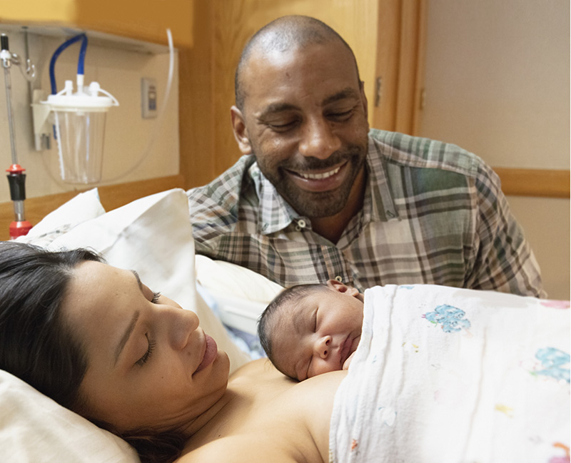 Family admiring their newborn baby at hospital with mother