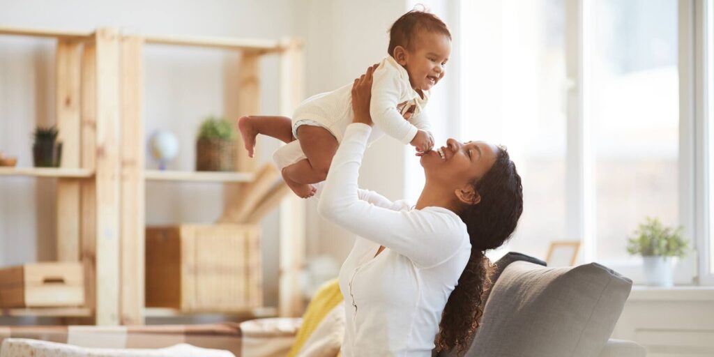 Caregiver lifting a smiling baby over her head