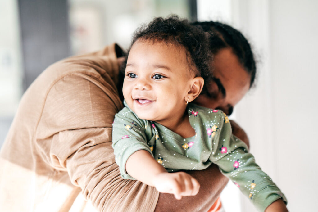 Caregiver hugging toddler, who is smiling