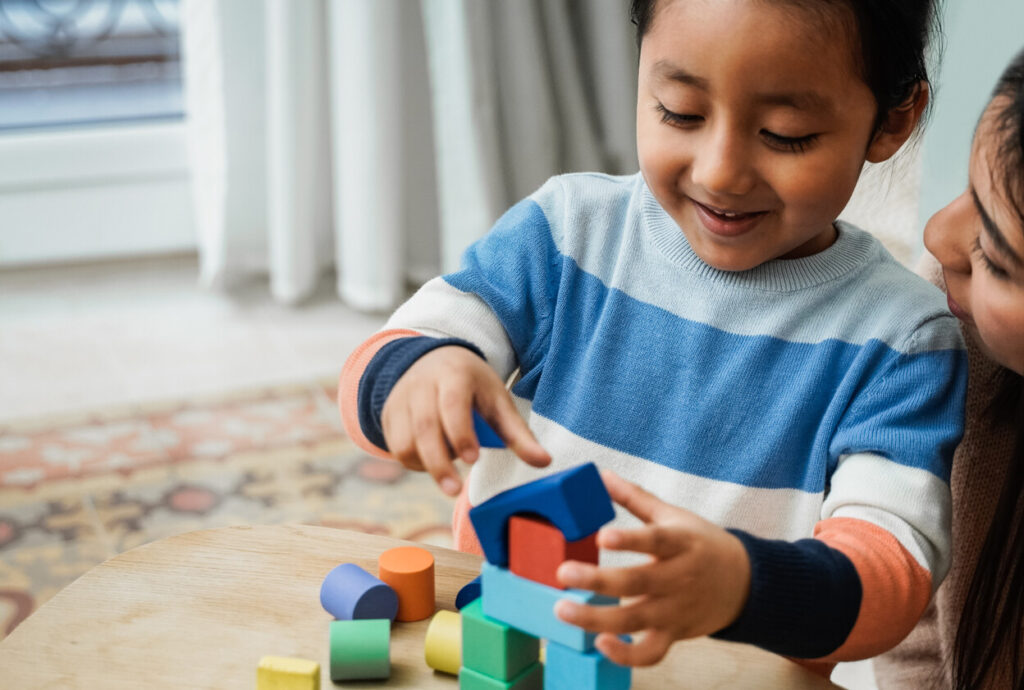 Young child and caregiver playing with blocks