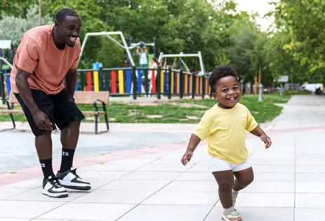 caregiver and young child playing in park