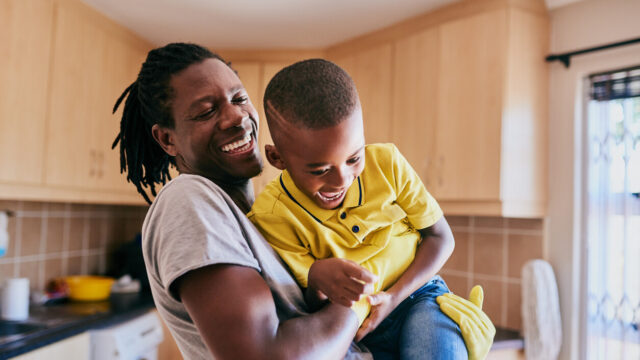 Caregiver playing with child in kitchen