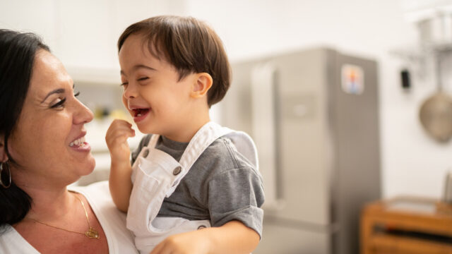 Toddler laughing at caregiver in a kitchen