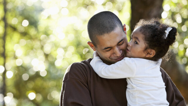 Caregiver holding and hugging toddler, who is kissing their cheek