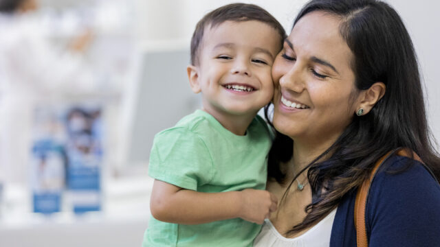 Caregiver holding young child, both laughing