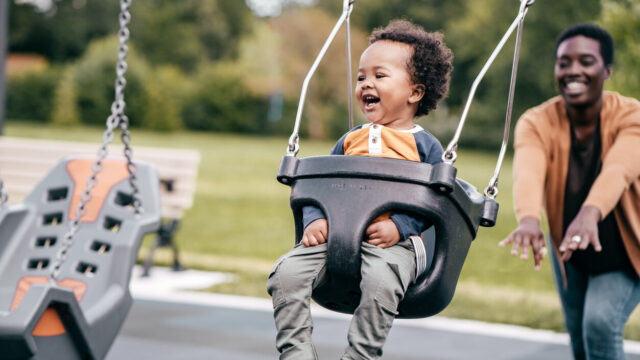 Caregiver pushing toddler on swing