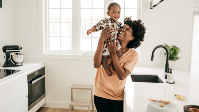 Caregiver holding up baby in kitchen