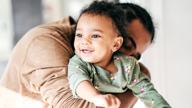 Caregiver hugging toddler, who is smiling