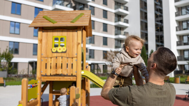 Caregiver playing with child at city playground