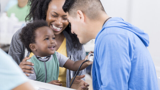 Caregiver, child, and pediatrician, all smiling.