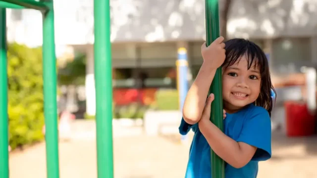 girl outside holding onto fence.