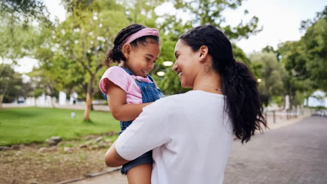 caregiver holding child at park.